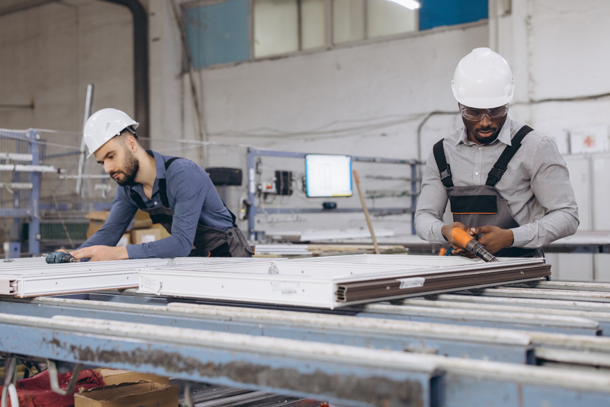 Factory workers assembling aluminum and pvc window frames